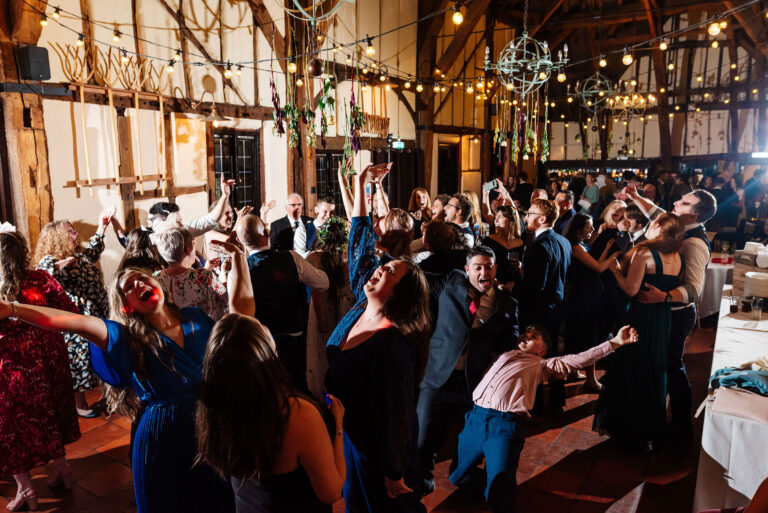 A group of people celebrate at an evening party or reception at the Tithe Barn at The Kingfisher in Bedford